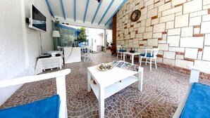An outdoor patio with a stone floor, white furniture, and a brick wall. - Nano Hotel (Cesme)