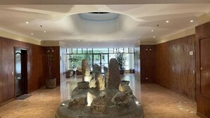 Un amplio vestíbulo con una fuente de roca central, paneles de madera y grandes ventanales que dejan entrar luz natural.