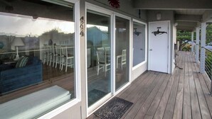A covered deck with glass doors, a bench, and outdoor furniture.