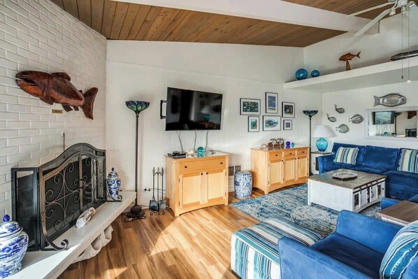 Ein Wohnzimmer mit Fernseher, blauem Sofa, Holzschränken und Fischdekoration.