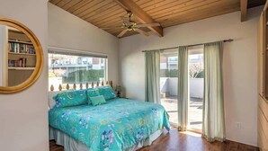 A bedroom with a bed, a ceiling fan, a window, and a view of the outside.