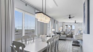 A spacious living area with a dining table, chairs, a sofa, and a bar area. - Guest Favorite| Gulf Front | Accommodates 12 |  Beach Serv. I Pet Friendly| (Miramar Beach)
