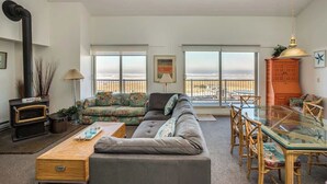 A living room with a sofa, a glass table, and a view of the sea. - Gearhart House G748 (Gearhart)