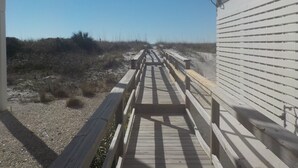 A wooden boardwalk leading to a building with a satellite dish.