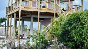 A two-story building with a balcony, a stone retaining wall, and a sign reading 'CapeSide Breeze.'
