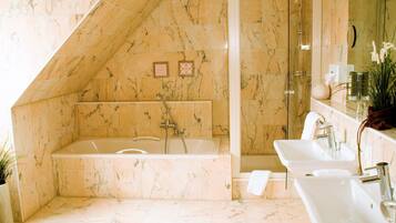 Une salle de bain avec une grande baignoire, deux lavabos et un espace douche.