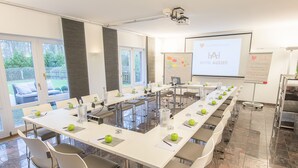 A conference room with a long table, chairs, a projector, and a presentation screen. - Hotel Auszeit (Isernhagen)