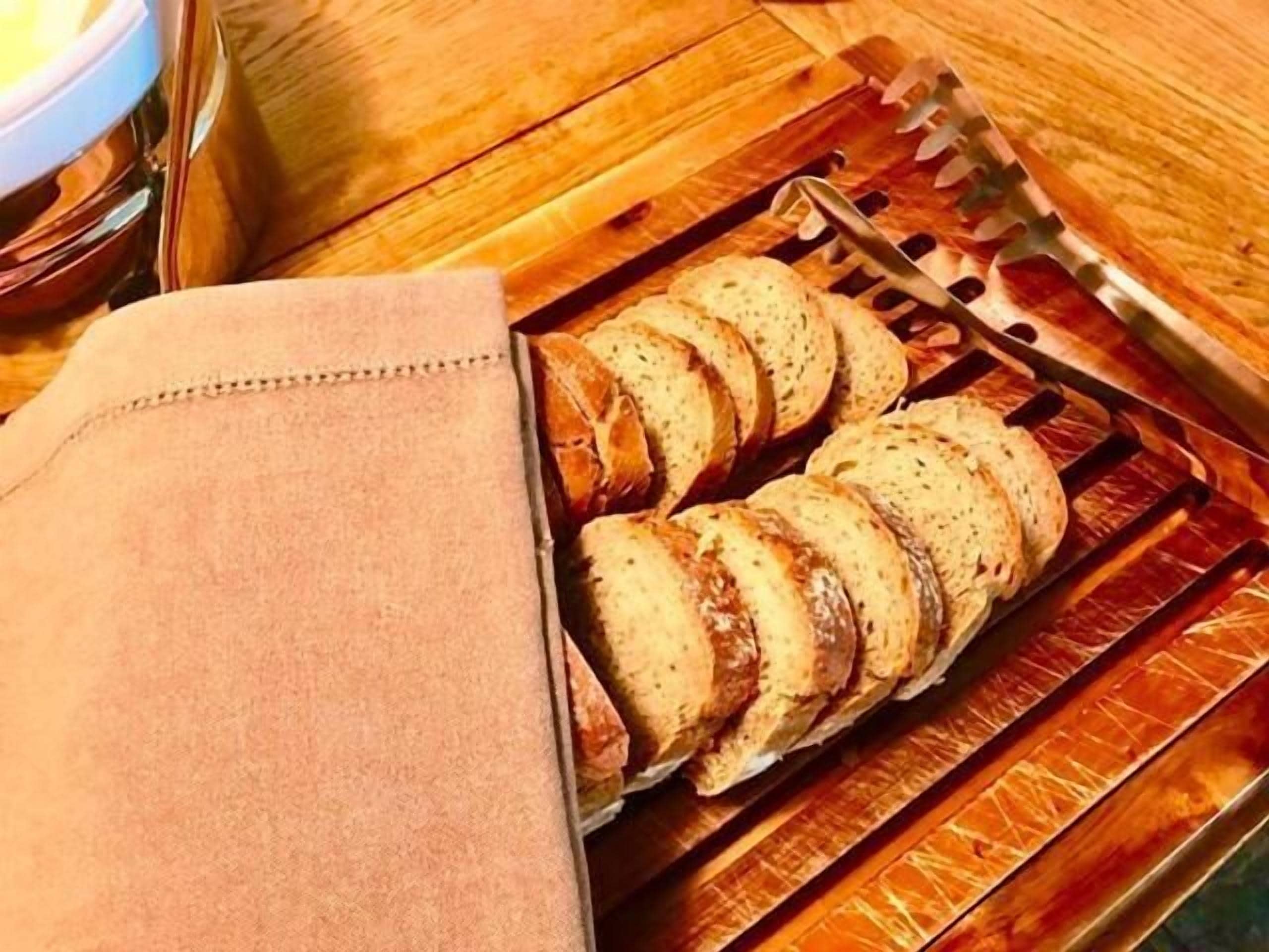 Een plank met sneetjes brood op een houten tafel.