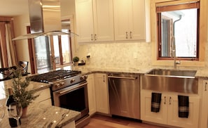 A modern kitchen with stainless steel appliances, a granite countertop, and a window with a view.
