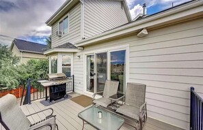 A covered patio with a grill, outdoor seating, and a sliding glass door leading to a deck. - Mountain View! Near Park and Rec Center w/ Pool! (Colorado Springs)