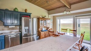 A kitchen with a marble countertop, stainless steel appliances, and wooden cabinets. - Pacific Terrace T401 (Gearhart)