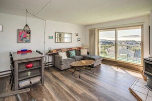 A modern living room with a sofa, coffee table, and a view of the city through large windows. - Gearhart House G665 (Gearhart)