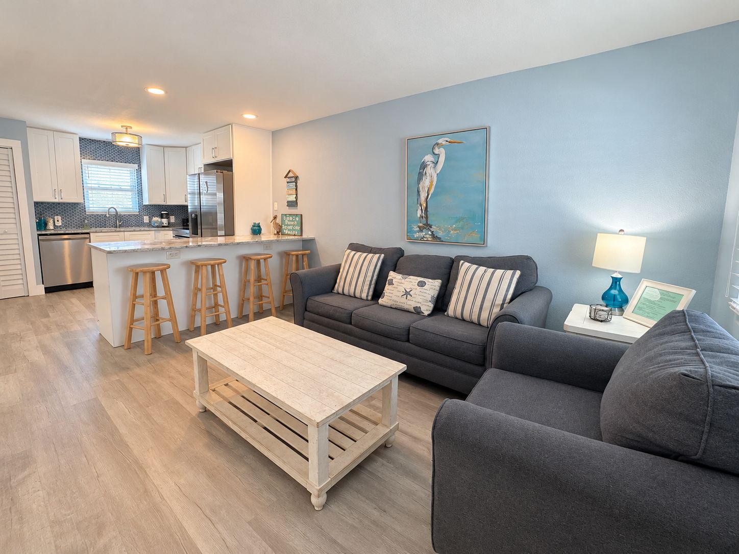 Un salon moderne avec un canapé gris, des tabourets en bois et une table basse.