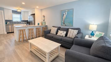 Un salon moderne avec un canapé gris, des tabourets en bois et une table basse.