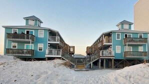 Ein strandnahes Anwesen mit zwei mehrstöckigen Gebäuden, ausgestattet mit Balkonen und Holztreppen.