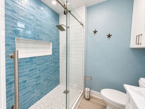 Une salle de bain avec une douche à parois de verre, des toilettes et un lavabo.