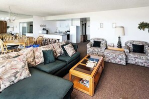 A modern living room with a sofa, a coffee table, and a dining area with chairs and a table.