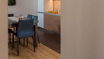 Una cocina moderna con armarios de madera, un comedor con mesa y sillas, y piso de baldosas.