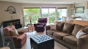A living room with a fireplace, a sofa, a loveseat, a coffee table, and a dining area with chairs and a table.