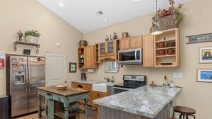 Una cocina con armarios de madera, un refrigerador de acero inoxidable, un microondas y una encimera de granito.