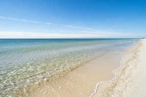 A beach with clear shallow waters and a sandy shore.