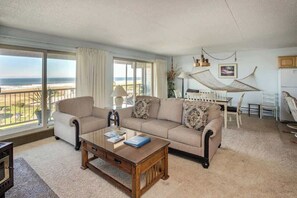 Un salon avec un canapé, une table basse et une vue sur la plage.