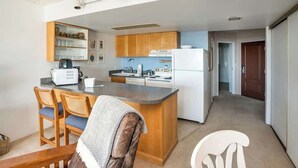 A compact kitchen with wooden cabinets, a central island, and a dining area with chairs.