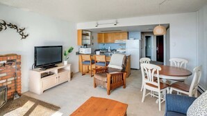A compact living space with a TV, seating area, kitchen, and a fireplace.