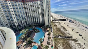 A high-rise hotel with a large pool area, beach access, and a view of the ocean.