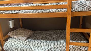 A bunk bed with patterned bedding, a wall-mounted light, and a woven basket.