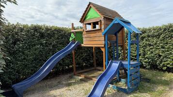 Una estructura de juego de madera con dos toboganes y una casita.