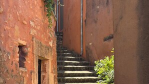 A narrow stone staircase leading up to a door, surrounded by red brick walls and potted plants.