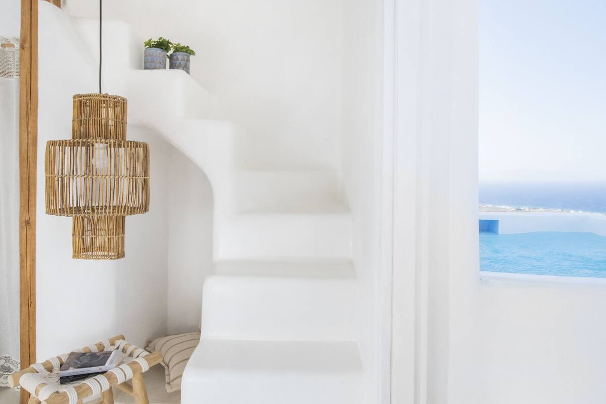 Una escalera blanca que conduce a un balcón con vista al océano.