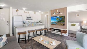 A modern hotel room with a kitchen, a dining area, a living room, and a TV. - Private lanai & heated pool - 1 block to the beach (Honolulu)