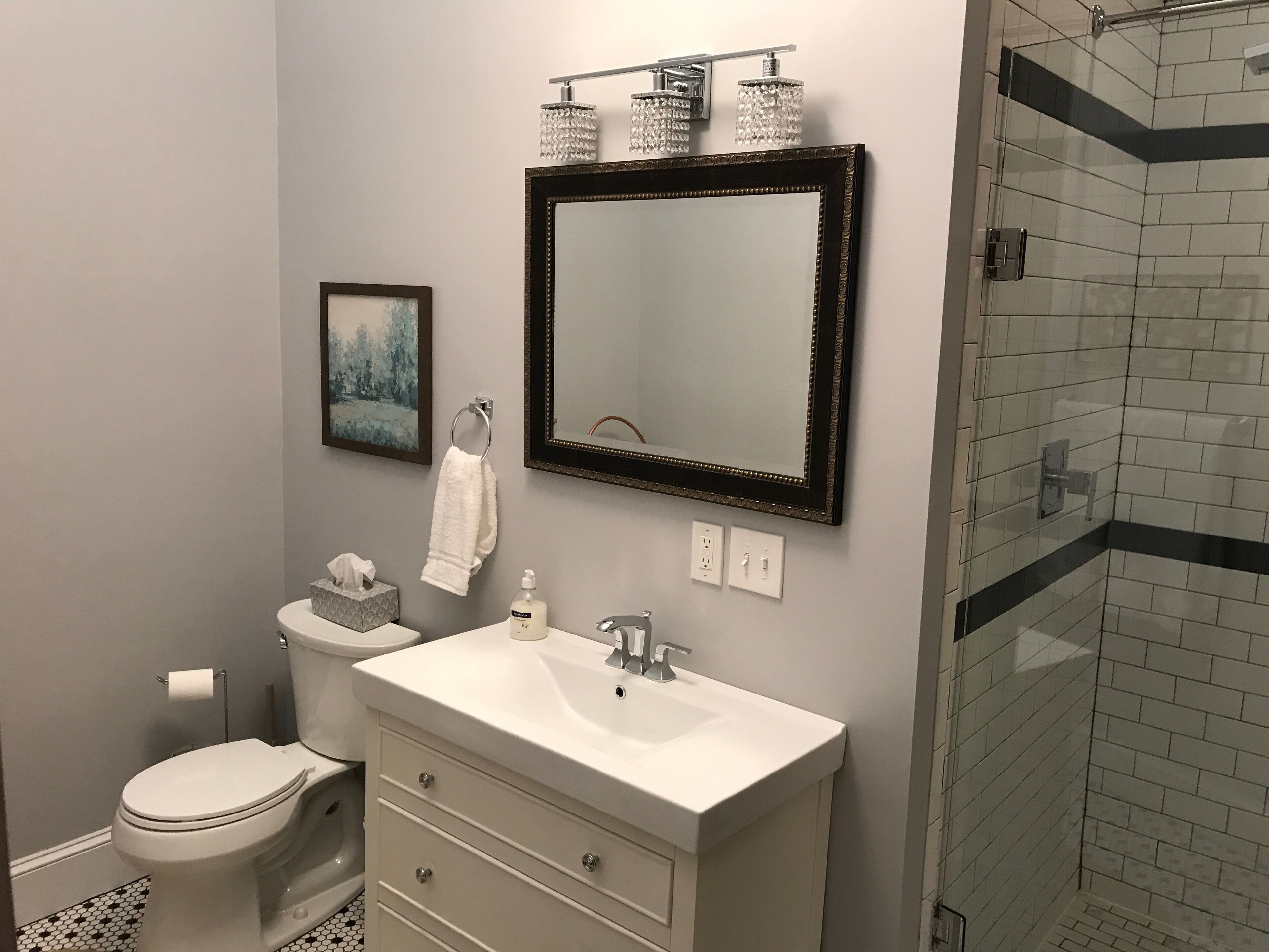 Een badkamer met toilet, wastafel, spiegel en douche.