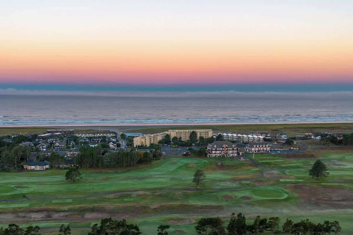 A golf course with a view of the ocean and a hotel in the background.