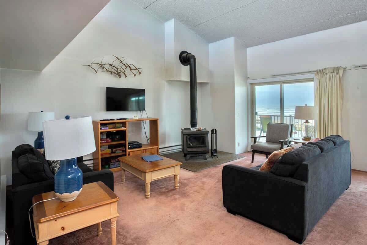 Ein Wohnzimmer mit einer Couch, einem Couchtisch, einem Fernseher, einem Bücherregal und einem Kamin.