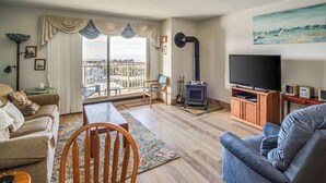Un salon comprenant un canapé, un téléviseur, une cheminée et un balcon avec vue.