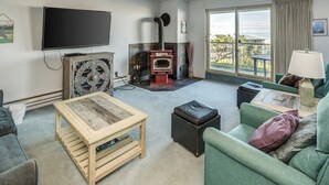 Un salon avec une cheminée, un téléviseur, un canapé et une vue sur l’extérieur.