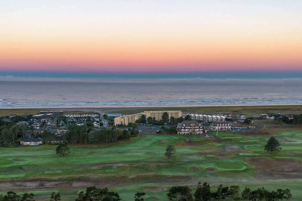 A coastal golf course with a large building complex in the background.