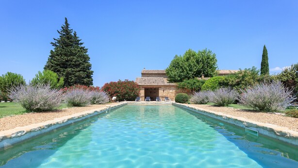 A clear pool with a stone building in the background. - La Louvière des Bruyères (Robion)