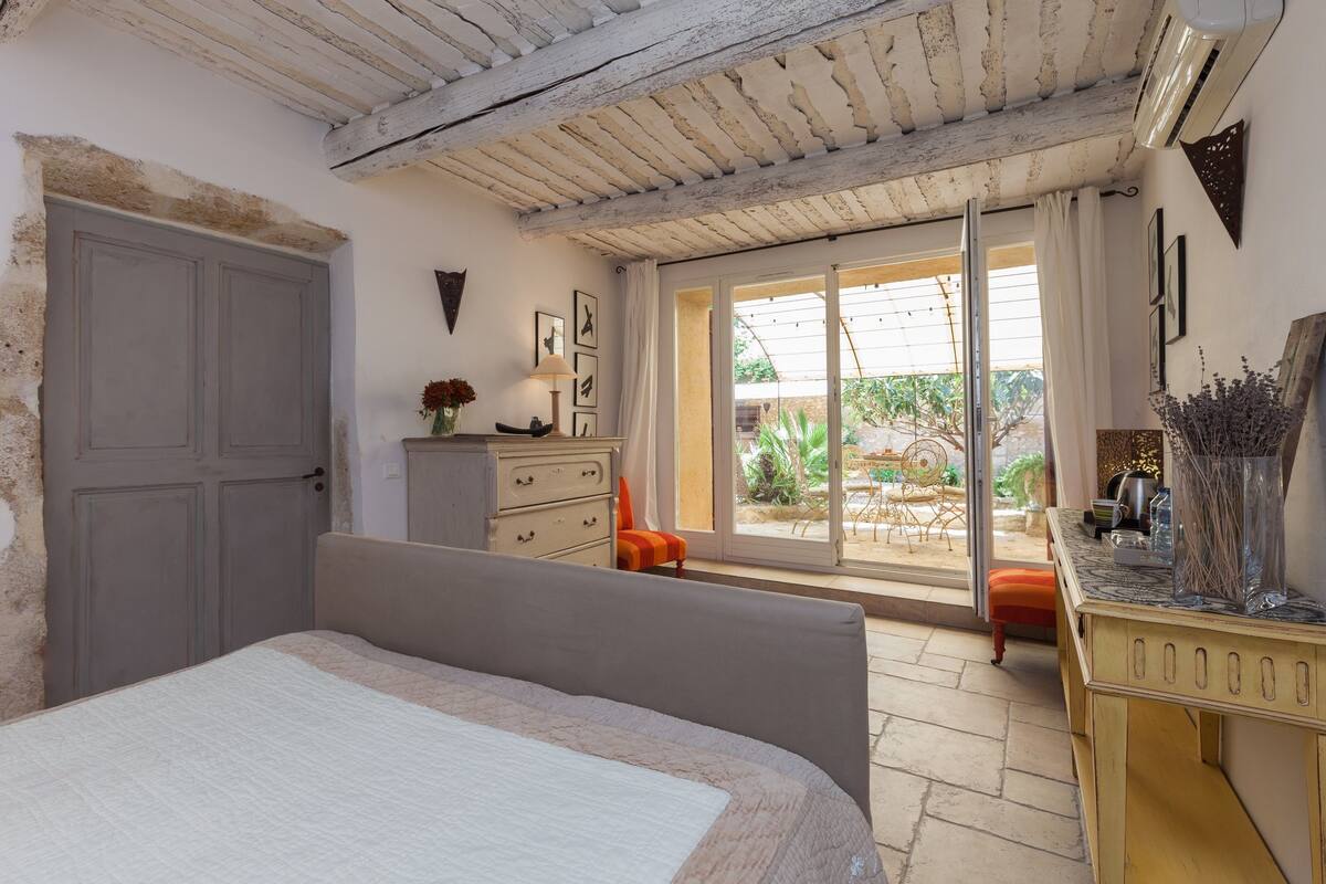 A bedroom with a bed, a dresser, a chair, and a sliding glass door leading to a patio.