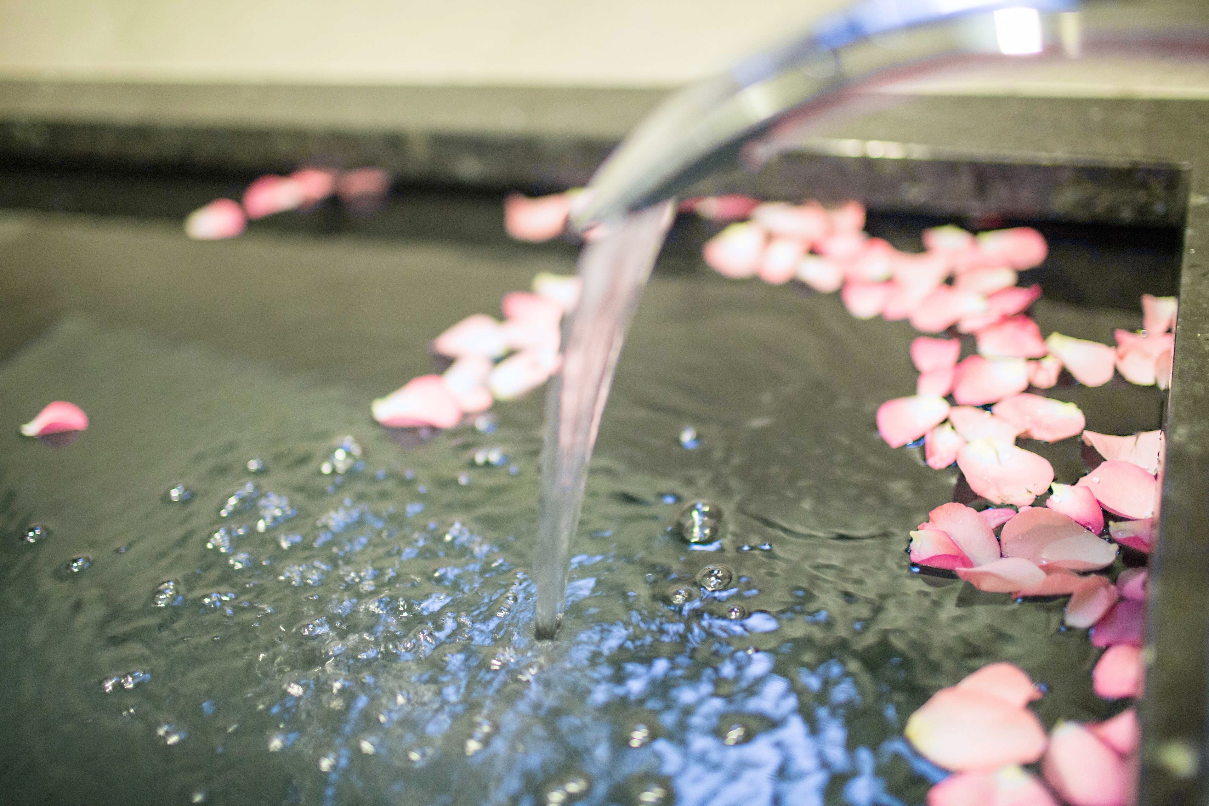 Ein Wasserspiel mit einem Wasserlauf und rosa Blütenblättern, die auf der Oberfläche treiben.