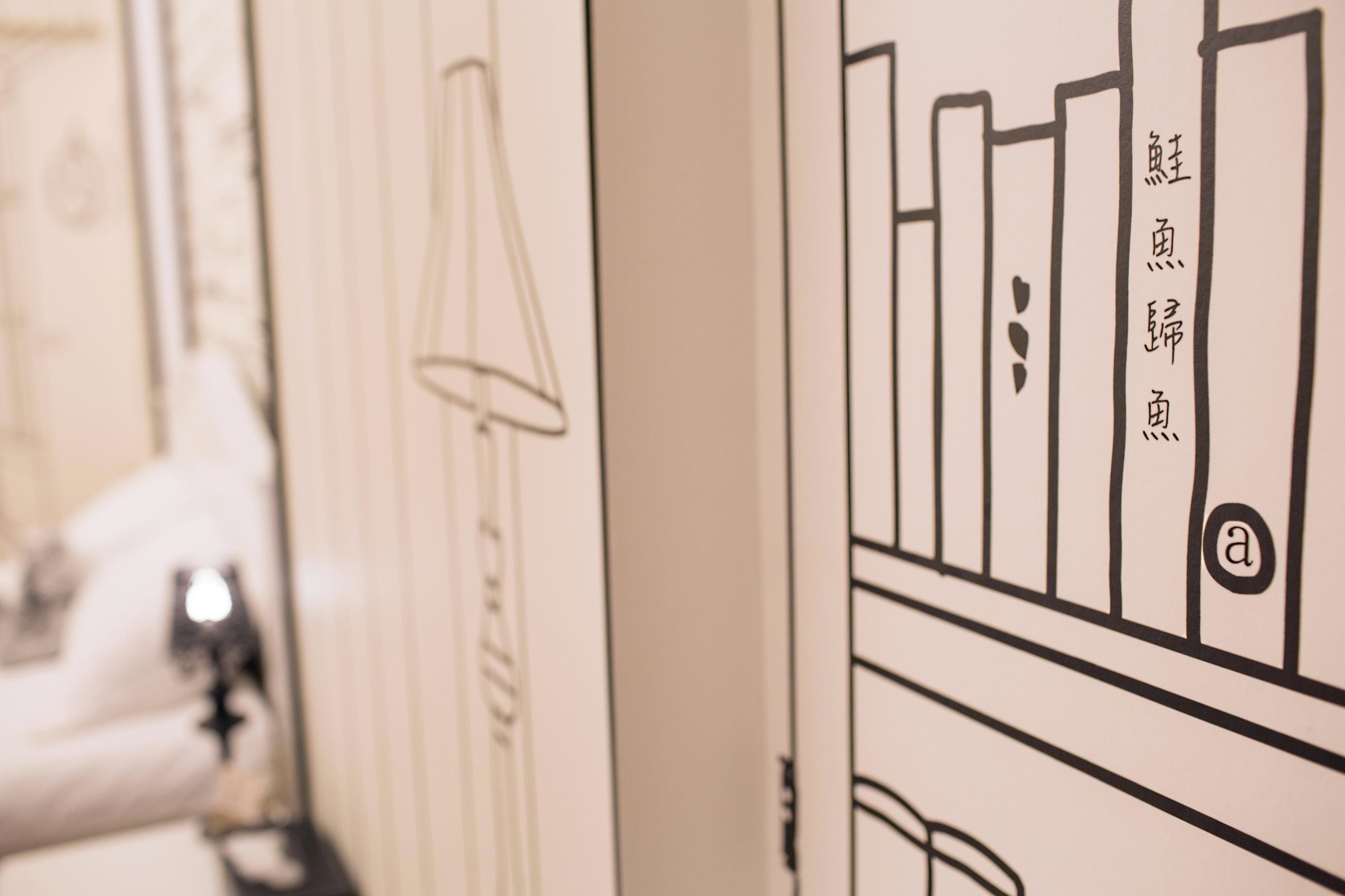 Primer plano de una pared con una lámpara y una estantería con libros y una letra 'a'.