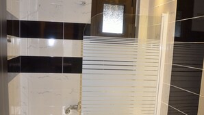 A modern bathroom with a glass-enclosed shower, a white toilet, and a black and white tiled floor. - 4-You Residence (Sithonia)