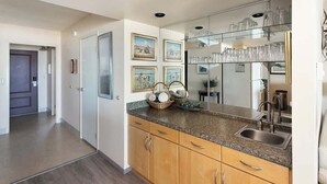Eine Küche mit Holzschränken, Granit-Arbeitsplatten, einer integrierten Spüle und einem Glastauschrank mit Gläsern.