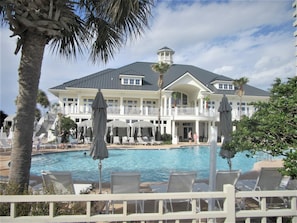 A large resort with a swimming pool, lounge chairs, and palm trees.