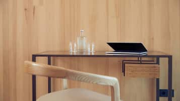A wooden wall, a glass bottle, two glasses, a laptop, and a chair with a wooden backrest.