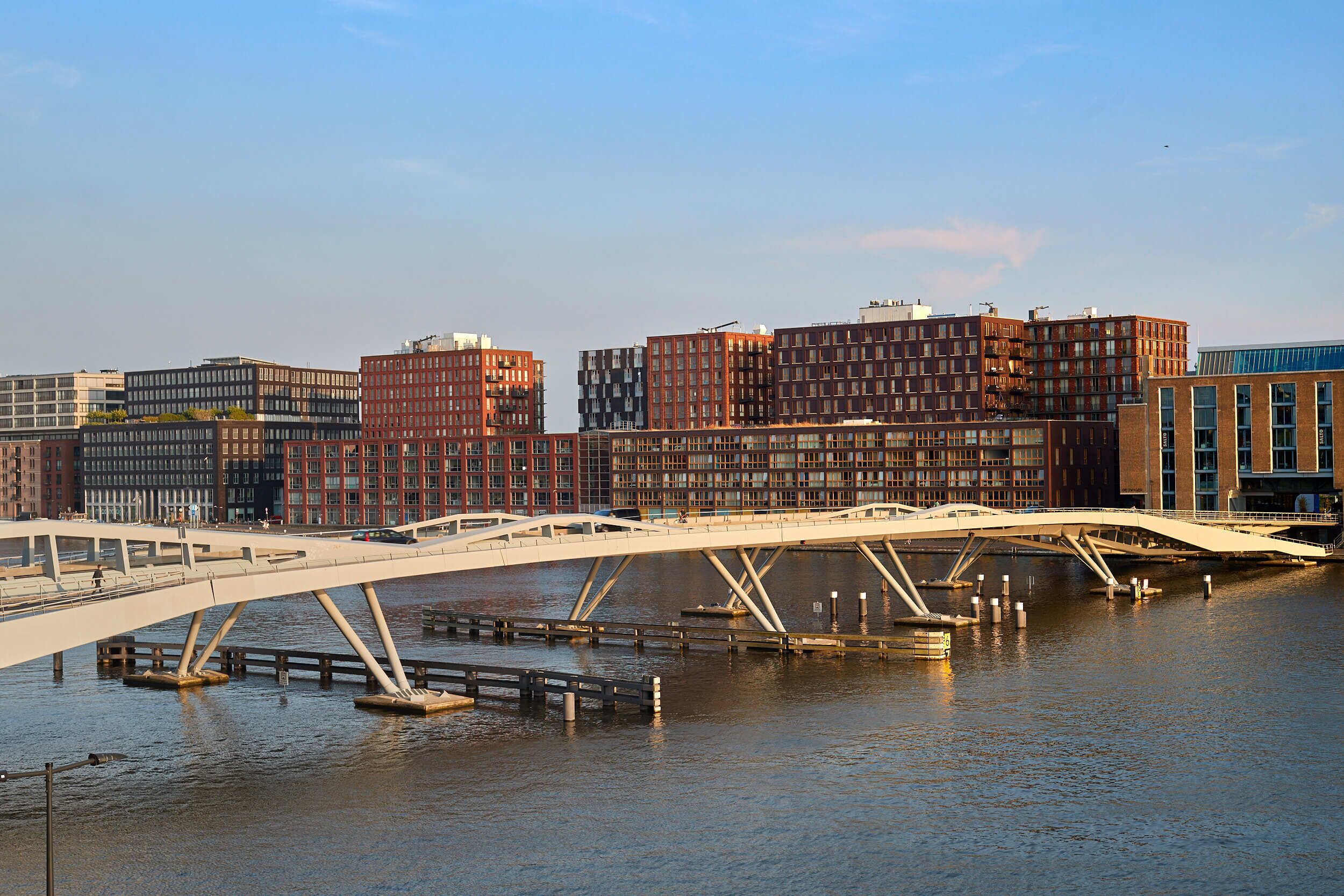 Un puente moderno sobre un río, con edificios altos al fondo.