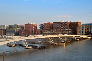 Un pont moderne enjambant une rivière, avec des immeubles de grande hauteur en arrière-plan.
